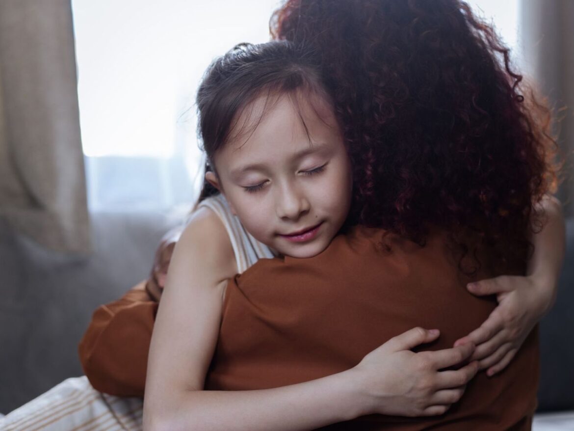 Ouder omhelst een jong kind in een rustig verlichte kamer