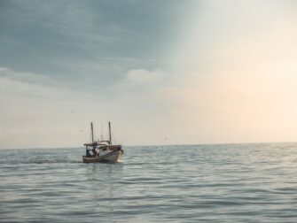 Kleine boot op kalm open water onder een lichte avondlucht