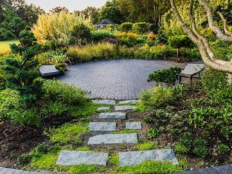 Rustige tuin met stapstenen, zitbanken en weelderige beplanting